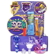 Front view of the "Thunderstruck" Smoking Box showing colorful purple packaging, stickers, a red lighter, hemp wrap pack, and a small iridescent glass rig.